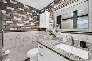 Full bathroom with curtained shower, vanity, and tile walls