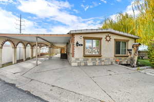 View of front of property featuring an attached carport, stucco siding, and concrete driveway