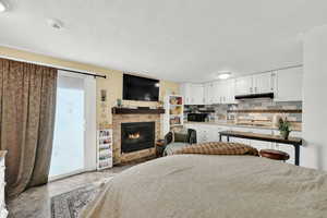 Bedroom with access to exterior, a glass covered fireplace, and a textured ceiling
