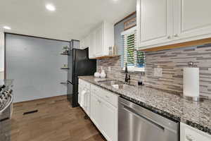 Kitchen featuring white cabinetry, stainless steel appliances, light stone counters, recessed lighting, and dark wood-type flooring