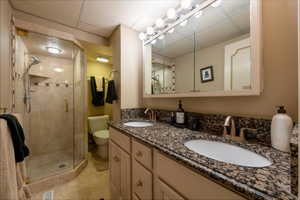Bathroom with a double vanity, a shower, light tile patterned floors and granite countertops