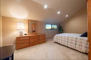 Bedroom with vaulted ceiling, recessed lighting, and light carpet
