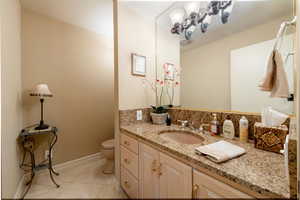 Half bath featuring vanity, light tile patterned floors and granite countertops