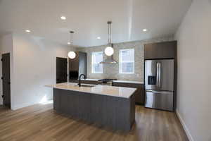 Kitchen with appliances with stainless steel finishes, dark brown cabinetry, hanging light fixtures, recessed lighting, and dark wood-style floors