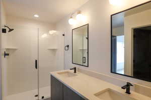 Full bath with double vanity, a stall shower, and recessed lighting