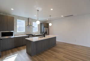 Kitchen with decorative light fixtures, wall chimney exhaust hood, decorative backsplash, appliances with stainless steel finishes, and modern cabinets