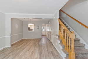 Unfurnished living room with light wood-style floors, crown molding, stairway, and a textured ceiling