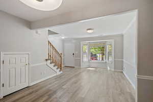 Foyer featuring stairway, light wood finished floors, and crown molding