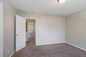 Carpeted spare room featuring attic access and a textured ceiling