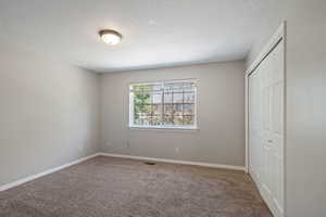 Unfurnished bedroom with a textured ceiling, carpet floors, and a closet