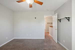 Carpeted empty room with ceiling fan and baseboards