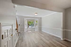 Entrance foyer with light wood-style flooring, stairway, a textured ceiling, and ornamental molding