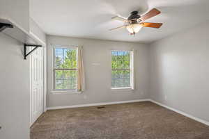 Unfurnished bedroom with multiple windows, carpet flooring, a closet, a ceiling fan, and a textured ceiling