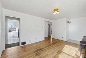 Unfurnished living room featuring light wood-type flooring and baseboards