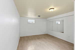 Basement with light wood-type flooring and a textured ceiling