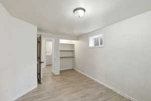Basement featuring light wood-type flooring, a textured ceiling, and washer / dryer