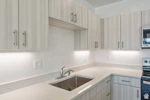 Kitchen featuring appliances with stainless steel finishes, modern cabinets, and light stone counters