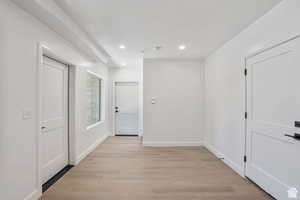 Hallway with light wood-style flooring and recessed lighting