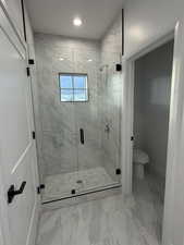 Bathroom with a shower stall, light marble finish floors, and recessed lighting