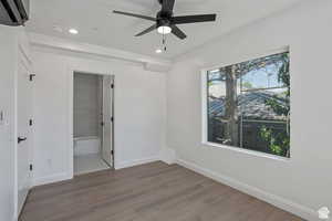 Unfurnished bedroom featuring wood finished floors, a ceiling fan, recessed lighting, and ensuite bath