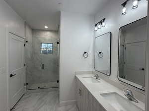 Full bath with double vanity, light marble finish flooring, a marble finish shower, and recessed lighting