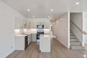 Kitchen with stainless steel appliances, a center island, recessed lighting, light wood-type flooring, and modern cabinets