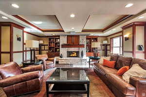 Living room with a tray ceiling, ornamental molding, a fireplace, and recessed lighting