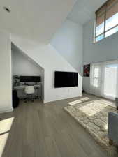 Home office featuring built in study area, a towering ceiling, wood finished floors, and a textured ceiling