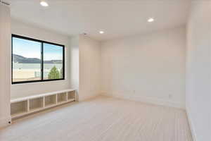 Empty room with light carpet, recessed lighting, and a water view