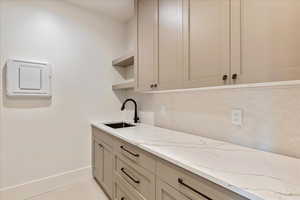 Bar area featuring open shelves and light stone counters