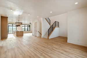 Unfurnished living room with recessed lighting, light wood finished floors, and stairway
