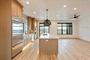 Kitchen with light brown cabinets, stainless steel appliances, open floor plan, a center island, and recessed lighting