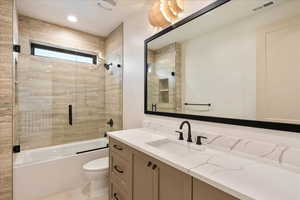 Bathroom featuring vanity and shower / bath combination with glass door