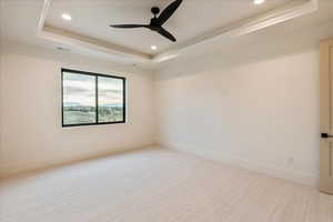 Spare room featuring a tray ceiling, light colored carpet, a ceiling fan, and recessed lighting