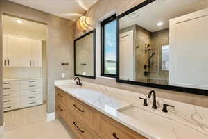 Full bath featuring double vanity, a tile shower, recessed lighting, and light tile patterned flooring
