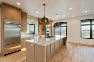 Kitchen featuring appliances with stainless steel finishes, light stone countertops, light wood finished floors, hanging light fixtures, and recessed lighting