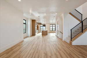 Unfurnished living room with light wood-style floors, recessed lighting, and stairway
