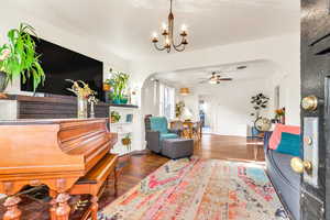 Living room with arched walkways, dark wood-style floors, and a ceiling fan