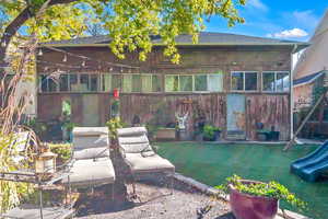 Rear view of house featuring a yard, a patio, roof with shingles, and a playground