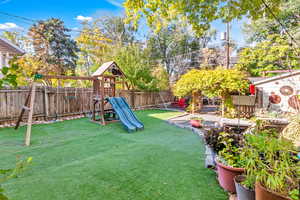 Fenced backyard with a playground and a patio