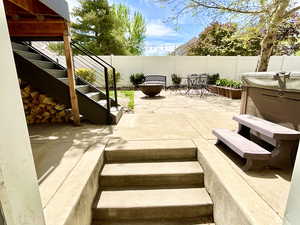 Fenced backyard featuring stairs from the walk-out basement, a patio area, and a hot tub during the summer.