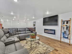 Living area with a glass covered fireplace, light wood-style flooring, and recessed lighting