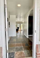 Hall with stone tile flooring, arched walkways, and recessed lighting
