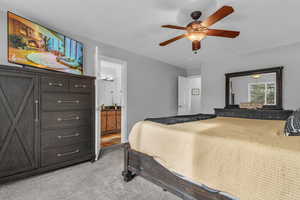 Bedroom with light carpet, connected bathroom, and a ceiling fan