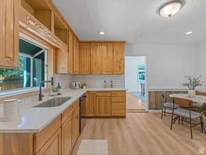 Kitchen with healthy amount of natural light, light wood finished floors, light stone counters, black dishwasher, and recessed lighting