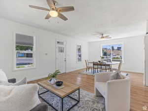 Living area with ceiling fan, plenty of natural light, and wood finished floors