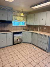 Kitchen with tile counters, dishwasher, and backsplash