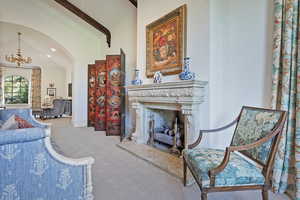 Sitting room with a chandelier, a premium fireplace, high vaulted ceiling, beam ceiling, and arched walkways