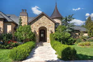 Doorway to property featuring stone siding, stucco siding, and a lawn