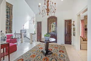 Foyer entrance with a chandelier, high vaulted ceiling, and light tile patterned flooring